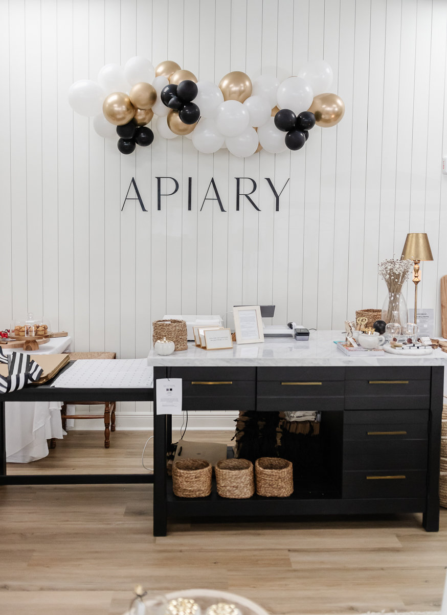 white wall with golden apiary sign and balloons